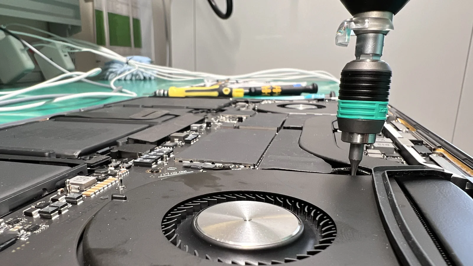 MacBook internals close-up with green precision screwdriver during keyboard replacement at WarriorMac