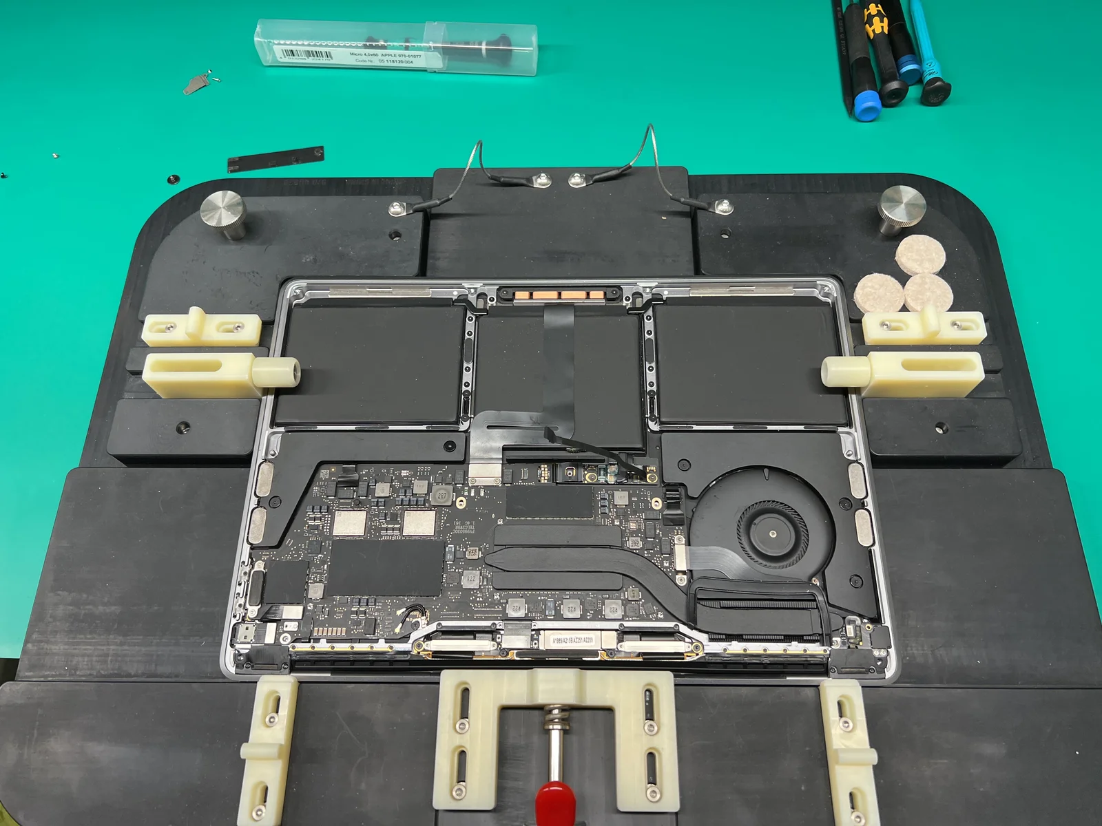 MacBook on professional repair jig with logic board and battery exposed during keyboard replacement at WarriorMac