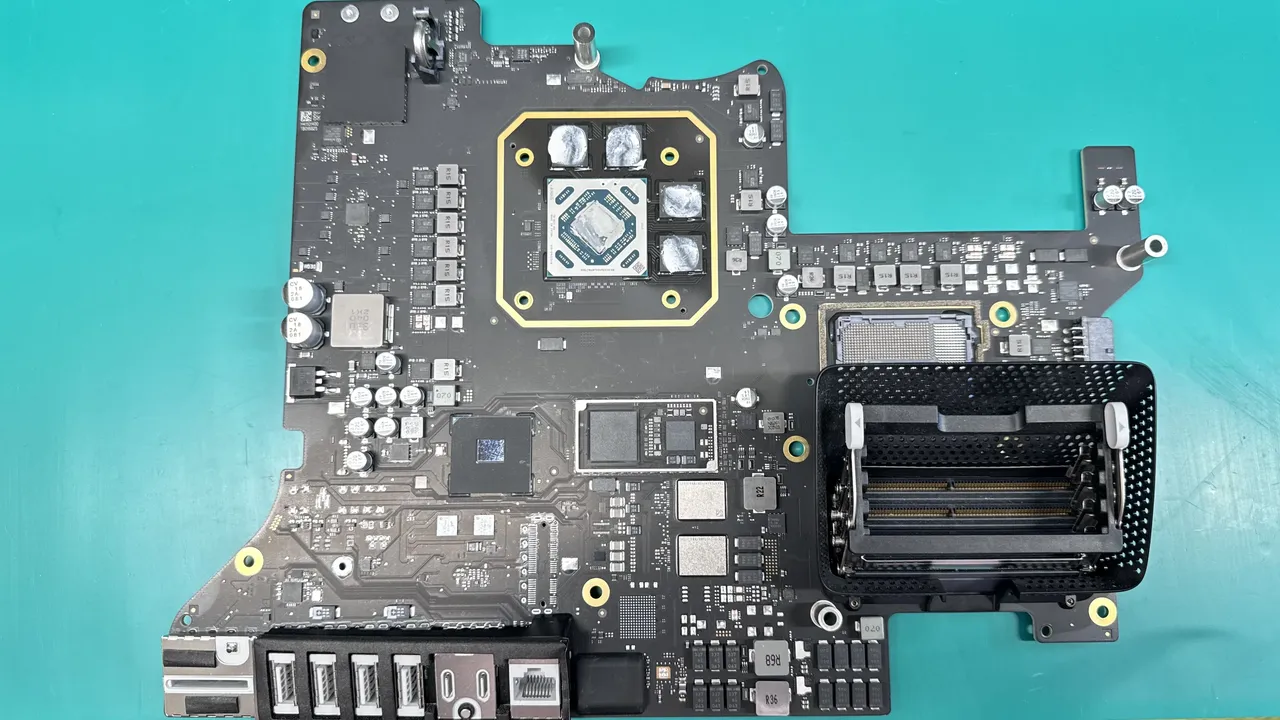 iMac logic board showing CPU with thermal compound, GPU, RAM slots, and SMD components during repair at WarriorMac Tampa